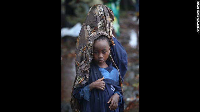 lija Siafa, 6, stands in the rain with his 10-year-old sister, Josephine, while waiting outside Doctors Without Borders' Ebola treatment center in Monrovia on August 17. The newly built facility will initially have 120 beds, making it the largest-ever facility for Ebola treatment and isolation. 