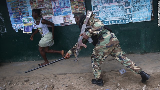 An Ebola Task Force soldier beats a local resident while enforcing a quarantine on the West Point slum on August 20.