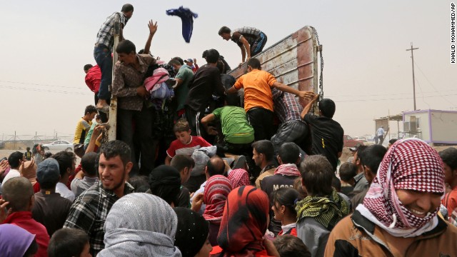 Displaced Iraqis receive clothes from a charity at a refugee camp near Feeshkhabour, Iraq, on Tuesday, August 19.