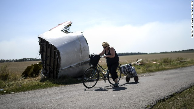 A woman walks with her bicycle near the crash site on Saturday, August 2.