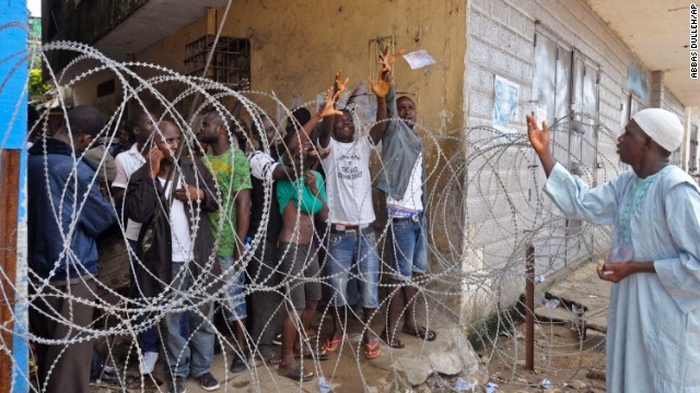 A humanitarian group worker, right, throws water in a small bag to West Point residents behind the fence of a holding area, as they wait for a second consignment of food from the Liberian government to be handed out in Monrovia, Liberia. The military began enforcing a quarantine on West Point, a congested slum of 75,000, fearing a spread of the Ebola virus.