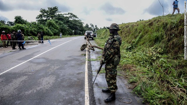 A guard stands at a checkpoint on Saturday, August 23, between the cities of Kenema and Kailahun in Sierra Leone, which have been quarantined due to the Ebola outbreak.