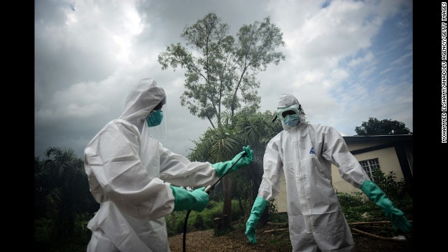 Volunteers working with the bodies of Ebola victims in Kenema, Sierra Leone, sterilize their uniforms on Sunday, August 24. 