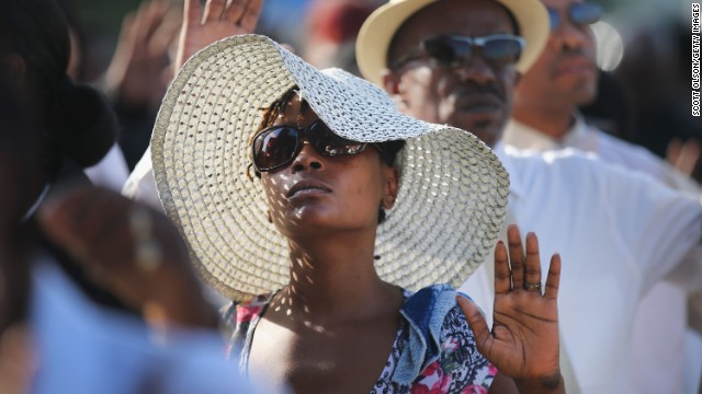Funeral attendees raise their hands as they wait in line to enter the church on August 25.