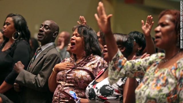 Funeral attendees sing before the start of the service on August 25.