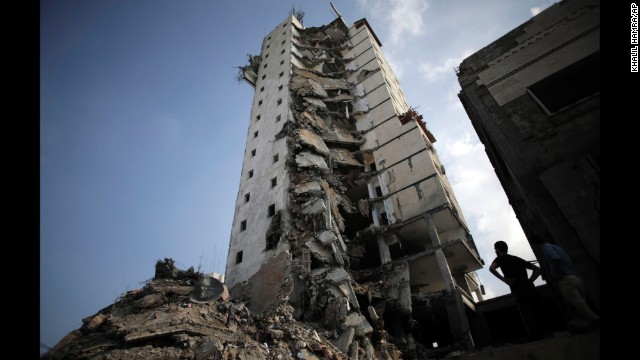Palestinians inspect the damage to a residential building following several late night Israeli airstrikes in Gaza City on August 26.