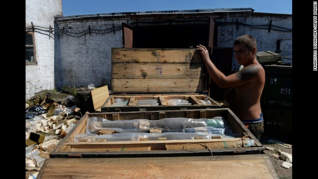A man opens a box on August 27 filled with rocket-propelled grenades left by the Ukrainian army in Starobecheve, Ukraine, after pro-Russian forces took control of the town.