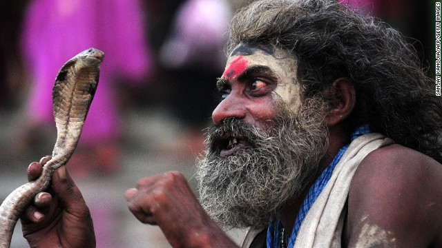 AUGUST 29 - SANGAM, INDIA: A snake charmer waits for alms from devotees during the Teej festival. Married women in Nepal and some parts of India fast and pray for long lives for their husbands during the three-day long festival, while unmarried women wish for handsome husbands and happy conjugal lives.