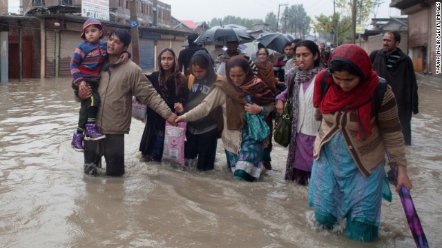 Kashmiris walk through floods that have claimed at least 20 lives and damaged dozens of homes.