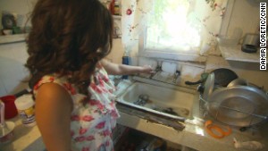 Sandra Tapia uses a hose hookup to a neighbor\'s house to wash dishes.
