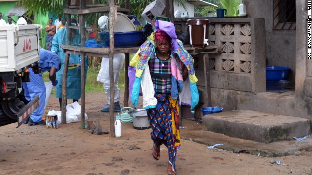 A woman in Monrovia carries the belongings of her husband, who died after he was infected by the Ebola virus.