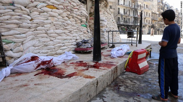 A boy looks at bodies lying outside a hospital after a barrel-bomb attack in Aleppo on Friday, September 5.