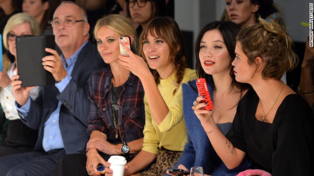Celebrities including Alexa Chung and Pixie Geldof whip out their smartphones on the front row at London Fashion Week
