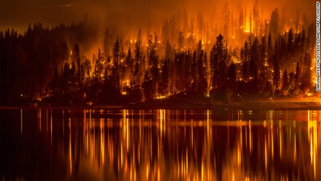 <strong>Wildfires:</strong> There's not a direct link between climate change and wildfires, exactly. But many scientists believe the increase in wildfires in the Western United States is partly the result of tinder-dry forests parched by warming temperatures. This photo shows a wildfire as it approaches the shore of Bass Lake, California, in mid-September. 