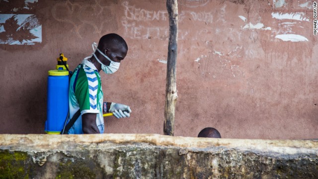 A health worker in Freetown, Sierra Leone, sprays disinfectant around the area where a man sits before loading him into an ambulance on Wednesday, September 24. 