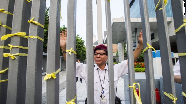 A police officer reacts after students in Hong Kong attach yellow ribbons to the barrier fences of government offices on Wednesday, September 24. 