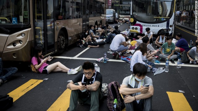 Pro-democracy protesters rest around empty buses as they block Nathan Road in Hong Kong on September 29. Multiple bus routes have been suspended or diverted.