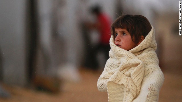 A Syrian refugee wraps herself in a blanket as she stands near tents in the Suruc district near Sanliurfa, Turkey, on Thursday, October 2. As many as 200,000 people have left the area surrounding the Syrian city of Kobani, also known as Ayn al-Arab, because of the militant group ISIS, the Syrian Observatory for Human Rights said in September.