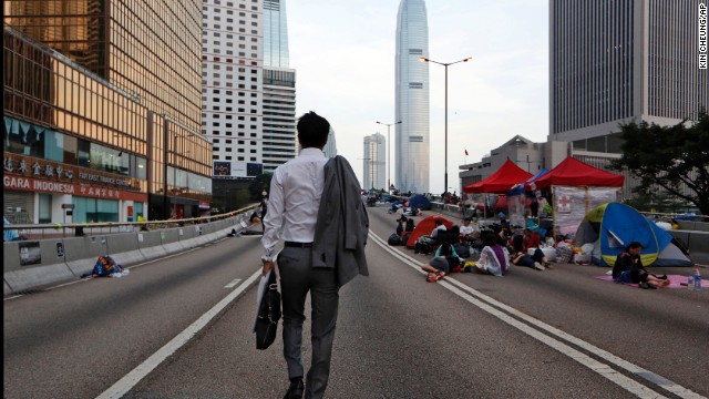 A man walks to work as pro-democracy demonstrators sleep on the road in the occupied areas surrounding the government complex in Hong Kong on October 6.