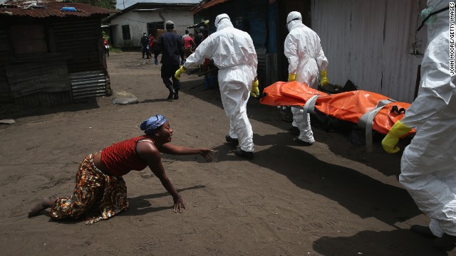 A woman crawls toward the body of her sister as a burial team takes her away for cremation Friday, October 10, in Monrovia. The sister had died from Ebola earlier in the morning while trying to walk to a treatment center, according to her relatives.
