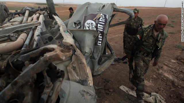 Peshmerga fighters inspect the remains of a car that reportedly belonged to ISIS militants and was targeted by a U.S. airstrike in the village of Baqufa, north of Mosul, on August 18.
