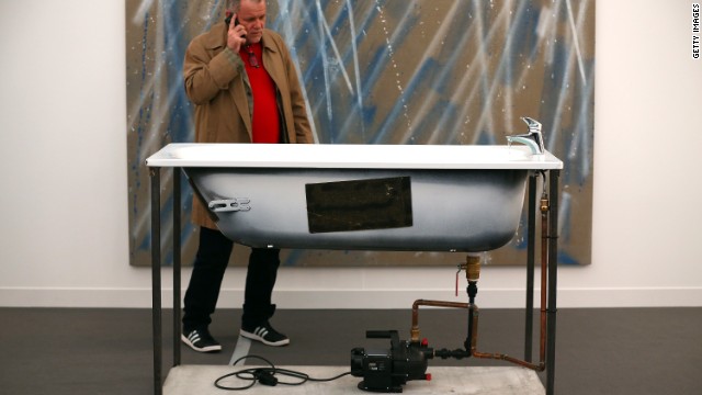 A visitor inspects a disembodied bath, better known as a sculpture by Oscar Tuazon titled "A Fountain".