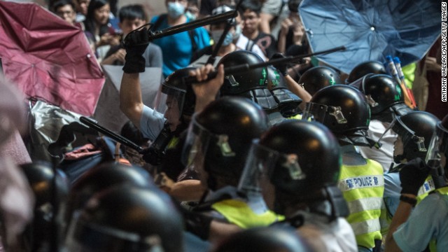 Police use batons to hit pro-democracy protesters who are using raised umbrellas for protection on October 17. 