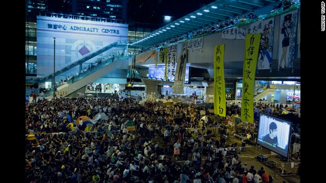Pro-democracy protesters at an occupied area outside the government headquarters in Hong Kong watch a live broadcast of talks between Hong Kong government officials and protesters on Tuesday, October 21.