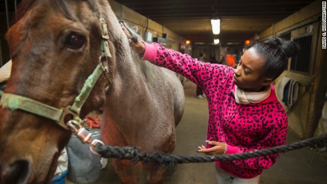 A young program participant grooms her horse inside a stable at the equestrian center. "We use horses as a hook to create pride, esteem and healing," Kelly said. "They learn that they have ability. They just have to unlock it."