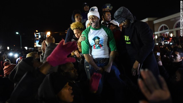 Demonstrators gather outside the police station on November 24. The man in the green sleeves is Michael Brown's stepfather, Louis Head. In a video of the scene from the New York Times, Brown consoles a tearful McSpadden and then tells the crowd to "burn this mother f---er down."