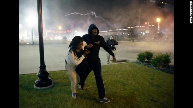 Protesters run for shelter as smoke fills the streets of Ferguson on November 24.