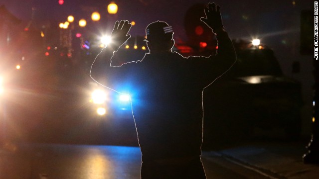 A protester stands in front of police vehicles with his hands up on November 24.
