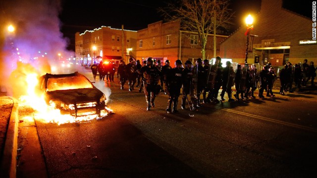 Police in riot gear move past a burning vehicle on November 24.