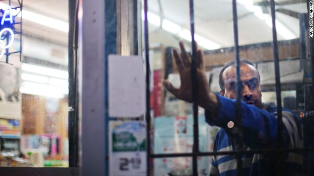 Nick Ahmad, owner of Elite Liquor, peers out of the store's door while waiting for customers on November 26. Ahmad paid $3,000 to hire several residents from the community to stand guard outside his business and deter looters.