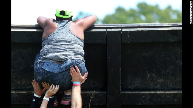 Competitors help a woman climb an obstacle Saturday, June 28, during the Spartan Race in Uncasville, Connecticut.