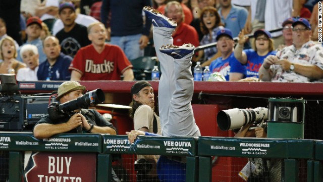 Photographers try to avoid Anthony Rizzo of the Chicago Cubs as he dives to catch a foul ball Sunday, July 20, in Phoenix.