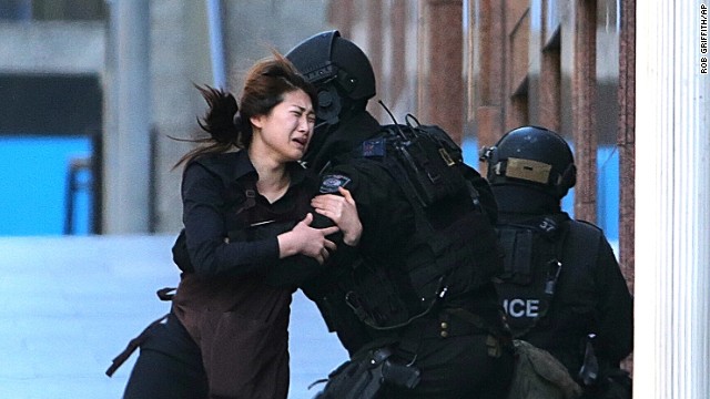 A hostage runs toward police on December 15. She was one of five people seen fleeing the cafe.