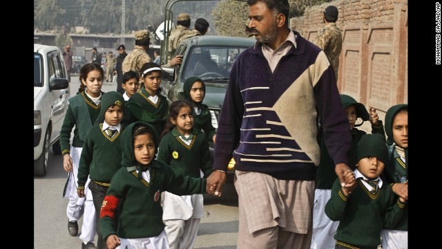 A plainclothes officer escorts rescued students away from the school on December 16.