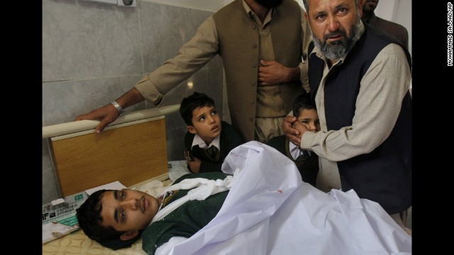 A man comforts a student standing at the bedside of an injured boy at a Peshawar hospital on December 16.