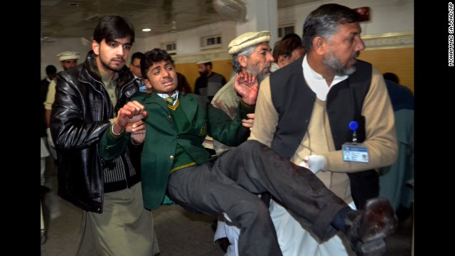 Volunteers carry a student at a hospital in Peshawar on December 16.