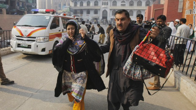 A man and woman rush to a Peshawar hospital treating victims of the attack on December 16.