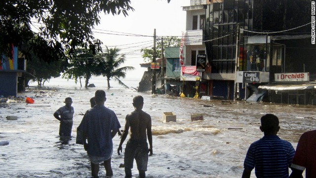 In this picture taken 26 December 2004, Sri Lankan pedestrians walk through floodwaters in a main street of Galle, after the coastal town was hit by a tidal wave.