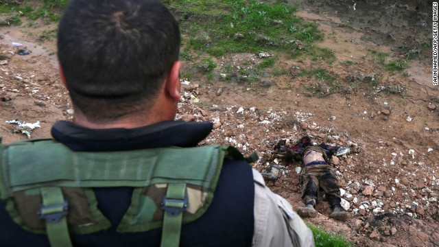 A Peshmerga fighter looks down at the body of an alleged ISIS fighter in Zummar, Iraq, on Thursday, December 18. 