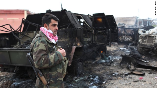 A Kurdish fighter stands next to a destroyed armored vehicle in northern Iraq on December 18. The vehicle was destroyed by an improvised explosive device placed by ISIS militants.