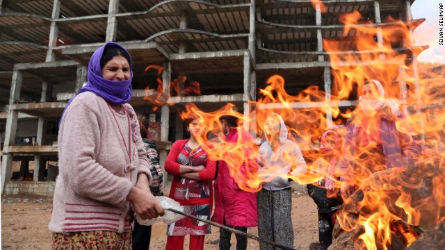 A Yazidi woman displaced by ISIS militants tends to a fire Wednesday, December 10, at a shelter in Dohuk, Iraq.