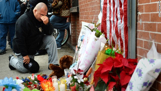 A New York City police officer kneels on Sunday, December 21, in front of a small memorial for two police officers who were killed in Brooklyn, New York, on Saturday. 