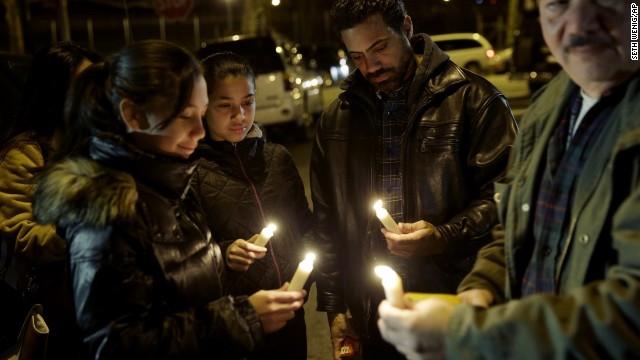 People light candles during a vigil on Sunday, December 21, for two NYPD officers who were ambushed and killed on Saturday. The two NYPD officers, Wenjian Liu and Rafael Ramos, were shot while sitting in their police car. Police have named Ismaaiyl Brinsley as the shooter.
