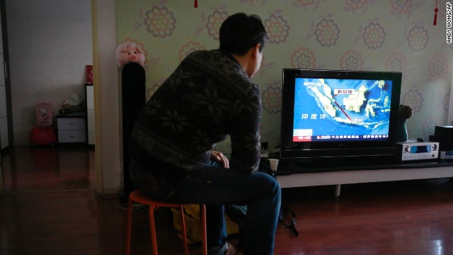 Jiang Hui, whose relatives were on board Malaysia Airlines Flight 370, which went missing on March 8, watches the news about the missing AirAsia flight at his house in Beijing.