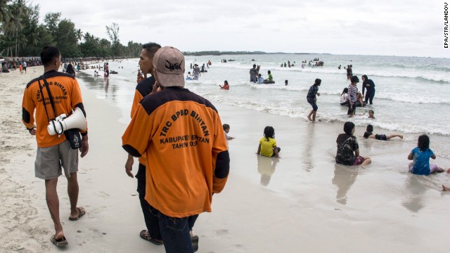 Members of the Indonesian Regional Disaster Management Agency walk at a beach as they search for the missing plane.