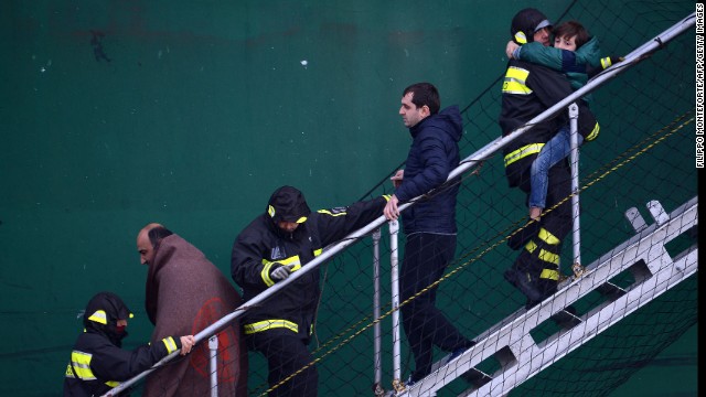 Survivors of the ferry fire are helped by rescuers as they disembark from a rescue ship in the Bari harbor in Italy on December 29.